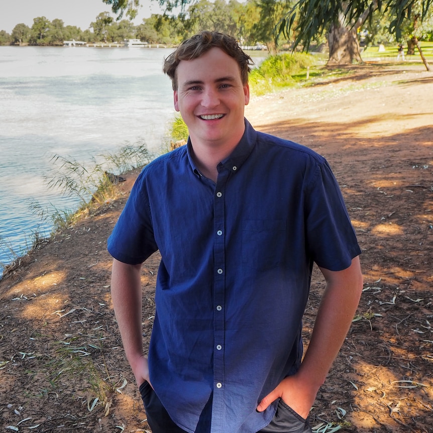 Andrew Murdoch standing on a riverbank in the shade of a giant gum tree.