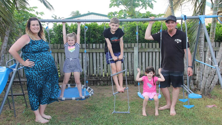 A family of five next to a swing set outside