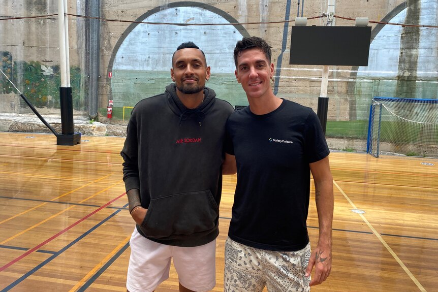 Nick Kyrgios and Thanasi Kokkinakis standing on a basketball court.