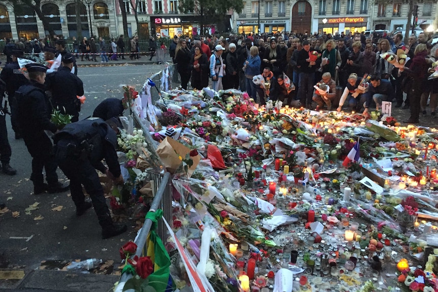 Hundreds of mourners gather around thousands of candles and flowers.