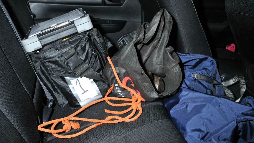 A black bag containing weights sitting on the back seat of a car.
