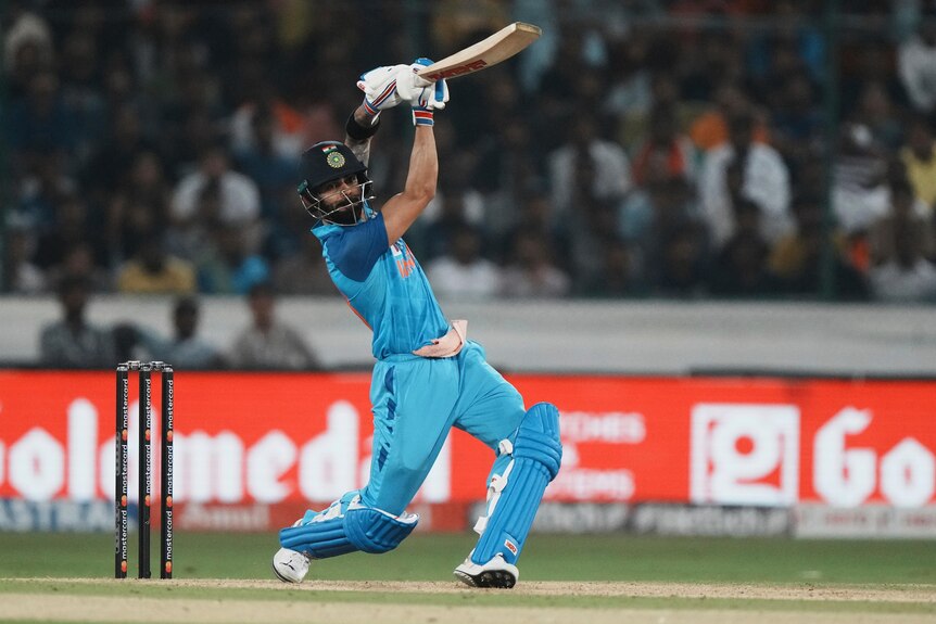 Indian cricketer Virat Kohli extends his bat in a follow-through after hitting the ball down the ground in a T20 International.