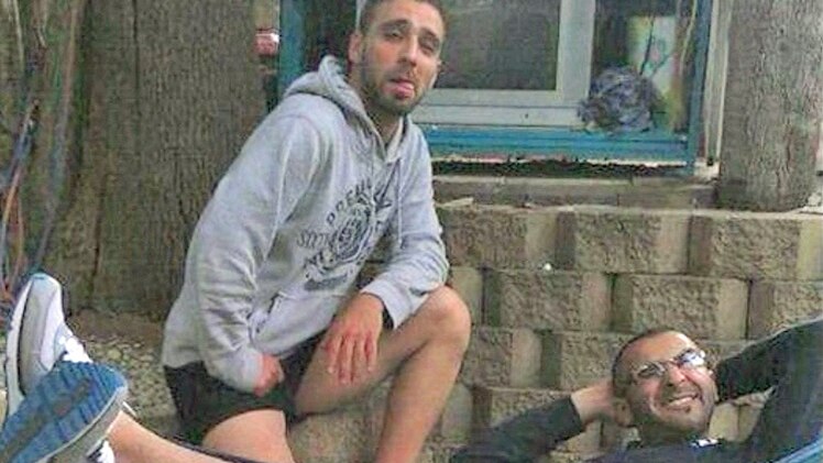 Omar Al-Kutobi kneels next to Mohammad Kiad as he lies in a hammock