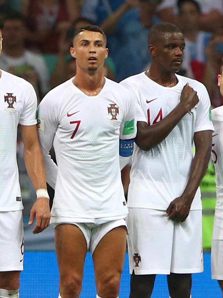 Four men in white Portugal uniforms stand in a row.