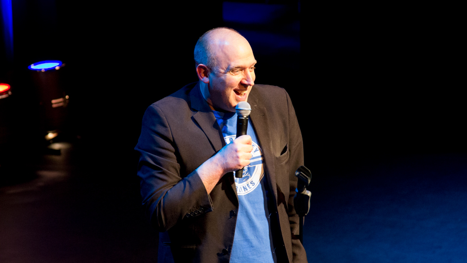 A man on stage with microphone.