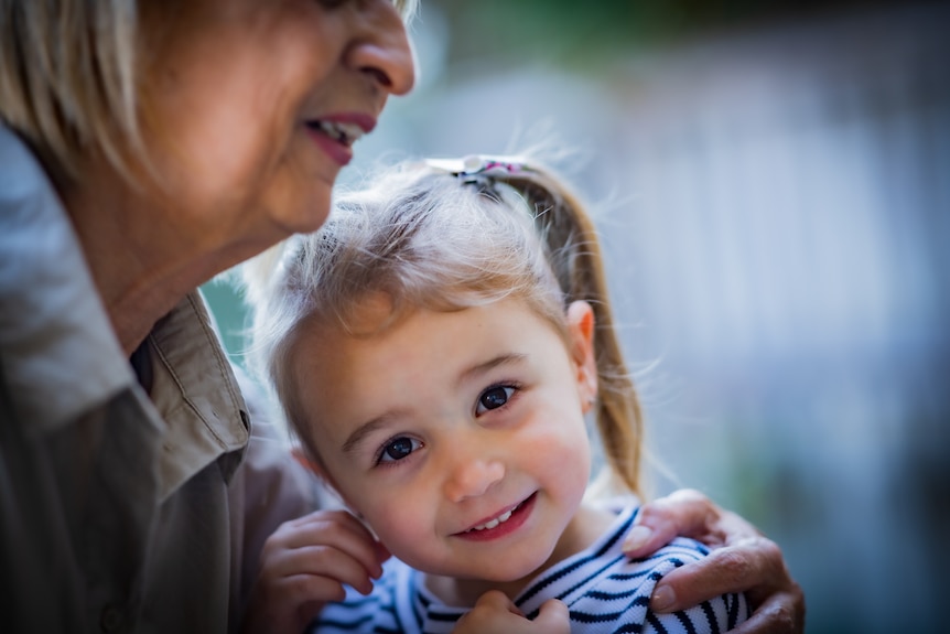 Rose holds her granddaughter Emilia close to her chest, as Emilia smiles at the camera.