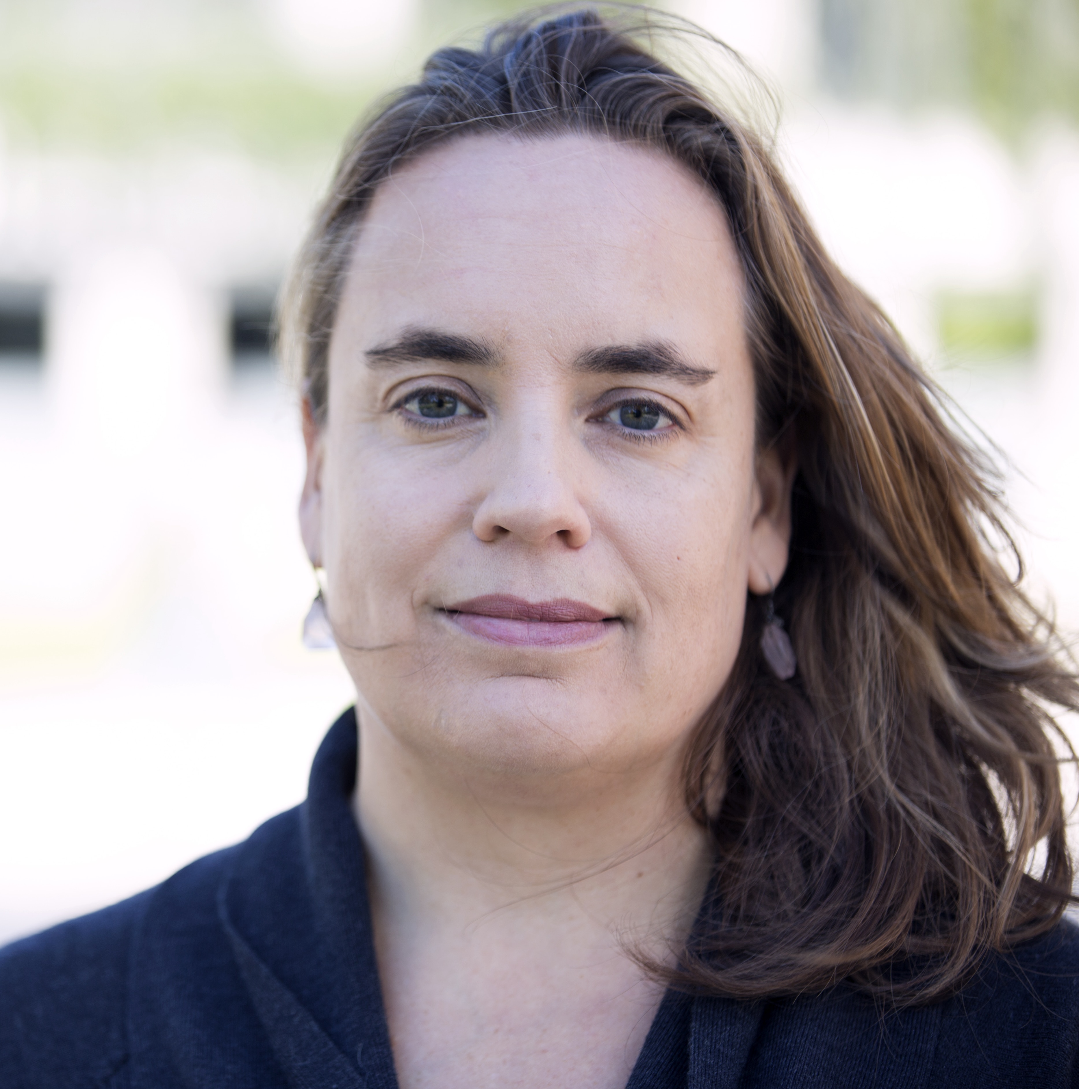 Uma mulher de cabelos castanhos olha para a câmera.