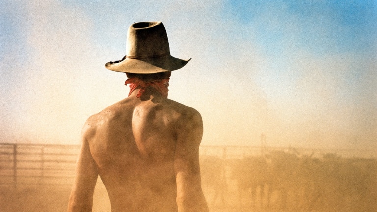 Dust surrounds a young cattle worker in a stockyard on a Northern Territory station.