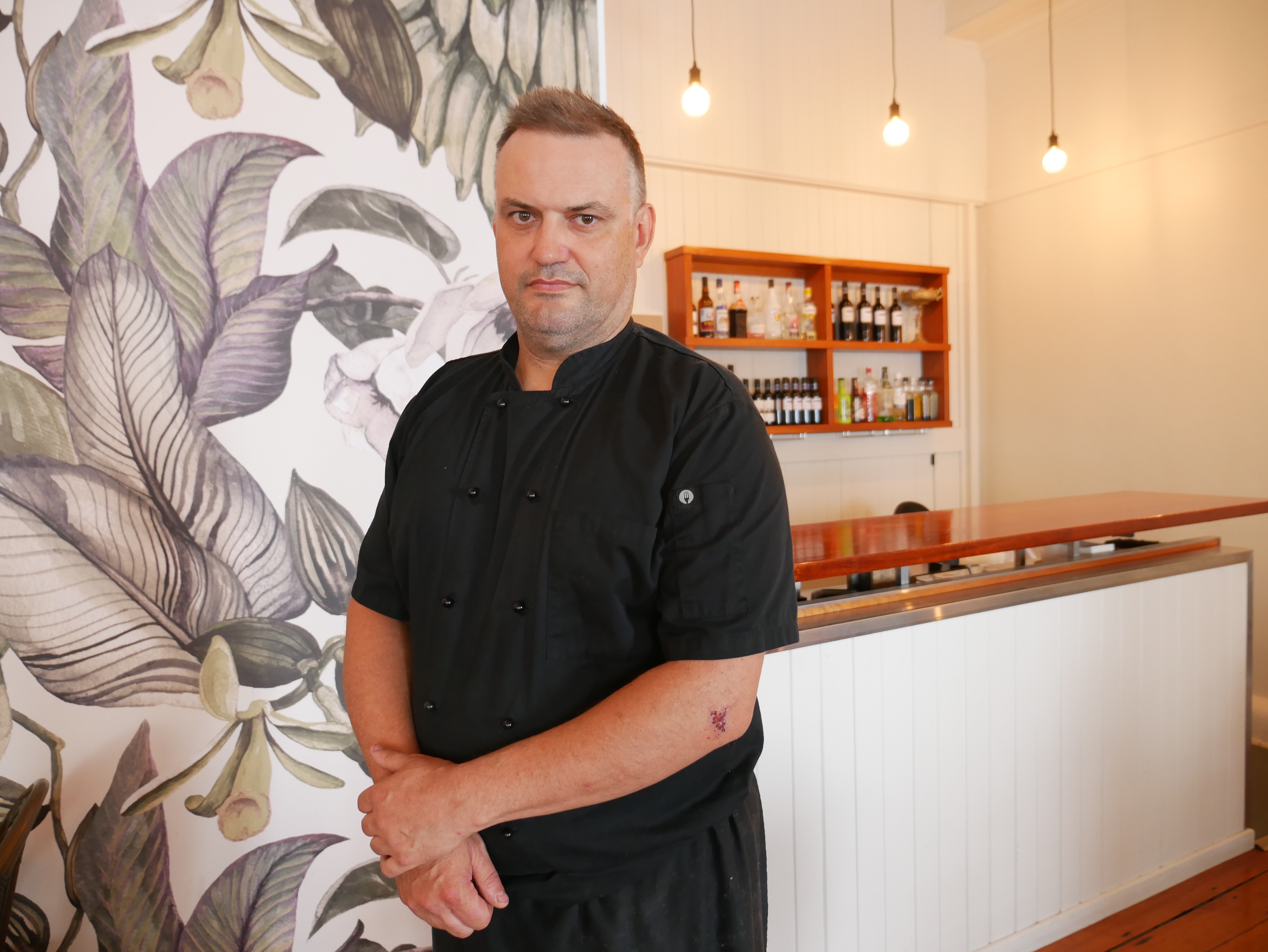 A man in a black shirt stands in a restaurant