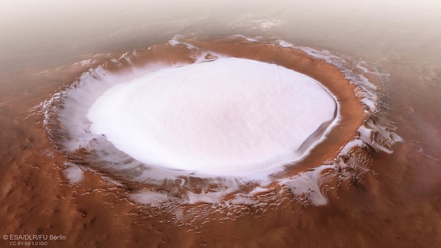 A vast crater in red dirt filled with white ice