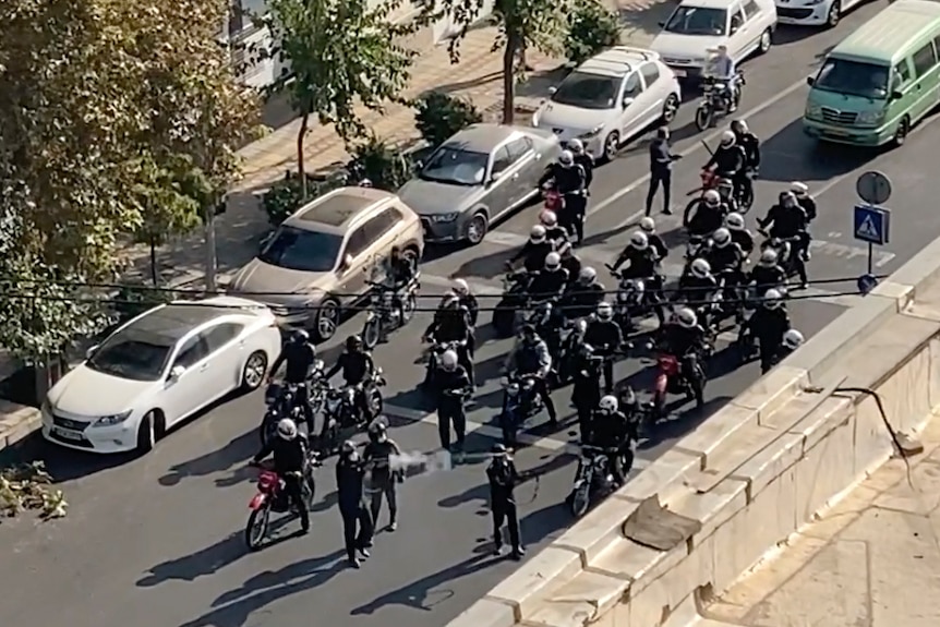 Dozens of police with weapons on motorcycles seen on road.