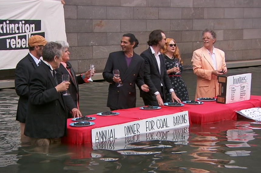 A group of climate activists staging a mock meal in the waters of the moat outside the National Gallery of Victoria.