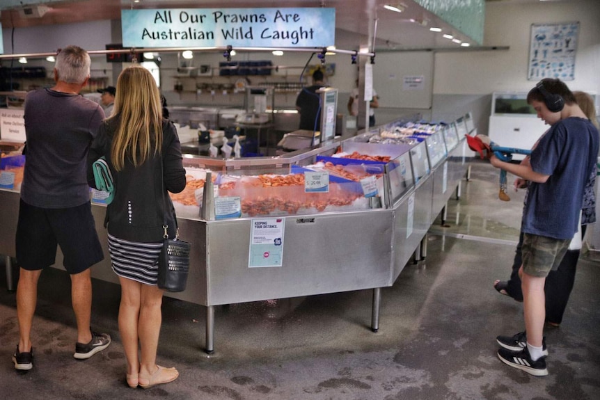 Customers stand at counter of Morgans Seafood  at Scarborough.