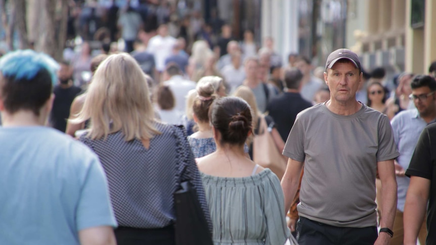 Dozens of people walk through Brisbane's Queen Street Mall, most are out of focus and the crowd stretches into the distance.