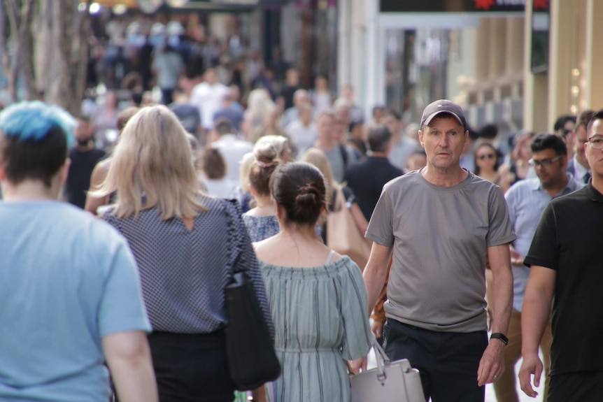 Dozens of people walk through Brisbane's Queen Street Mall, most are out of focus and the crowd stretches into the distance.