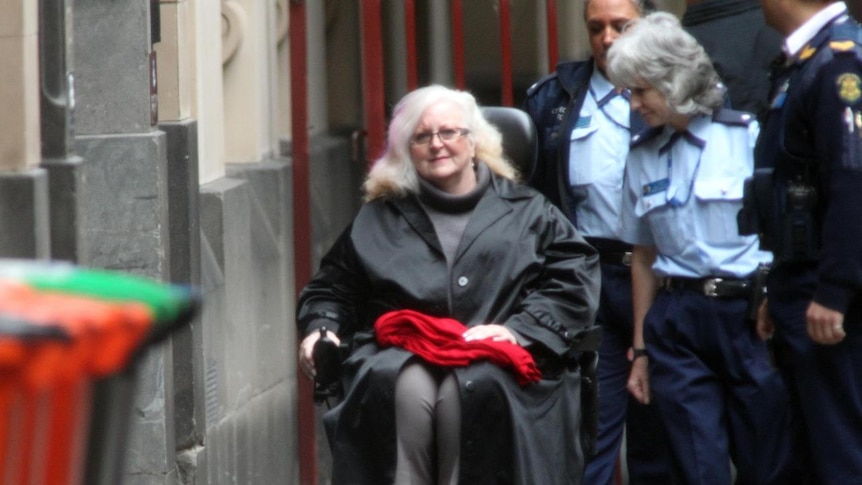 Judy Moran, surrounded by police, arrives at Melbourne's Supreme Court in a wheelchair on March 3, 2