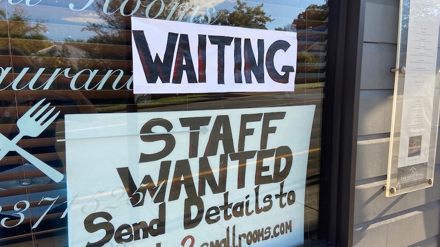 A sign saying 'staff wanted' in the window of a restaurant.