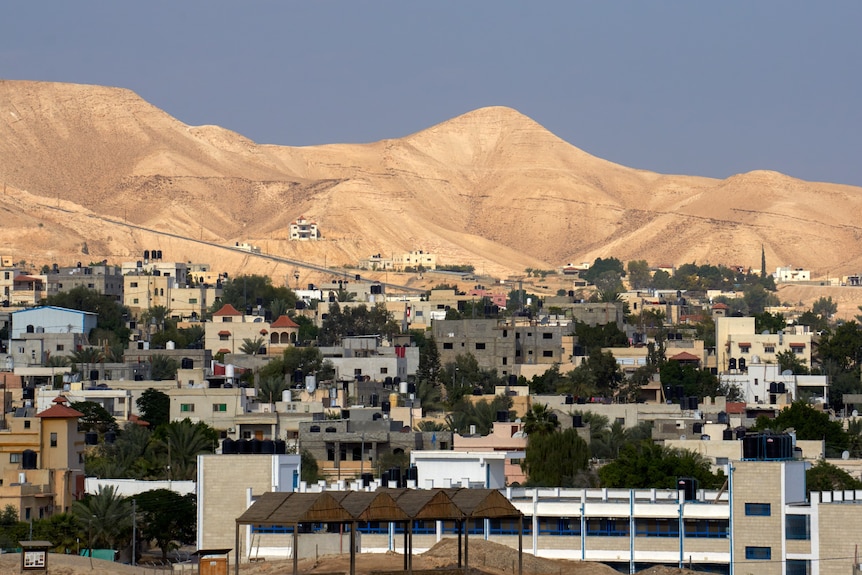 Small houses in front of barren desert hills.