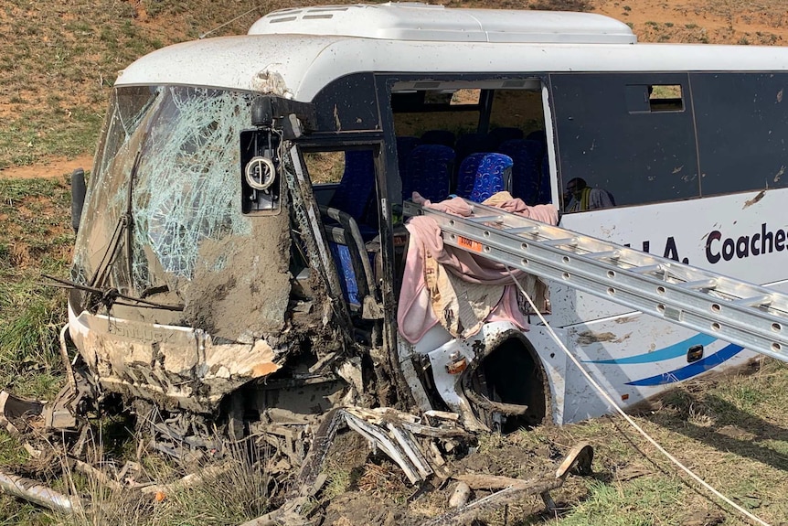 A smashed up bus with a ladder resting in the window