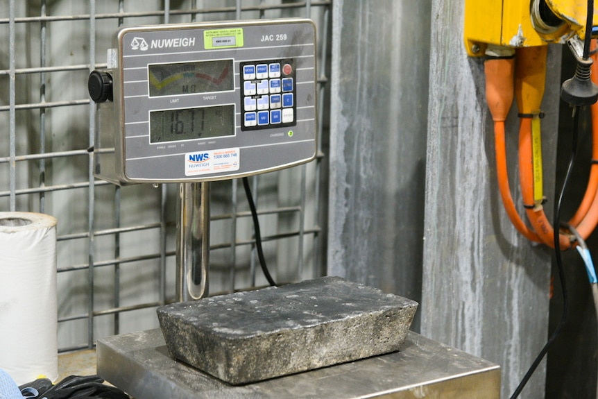 A silver-coloured metal bar on a set of scales that say it weighs 16 kilograms