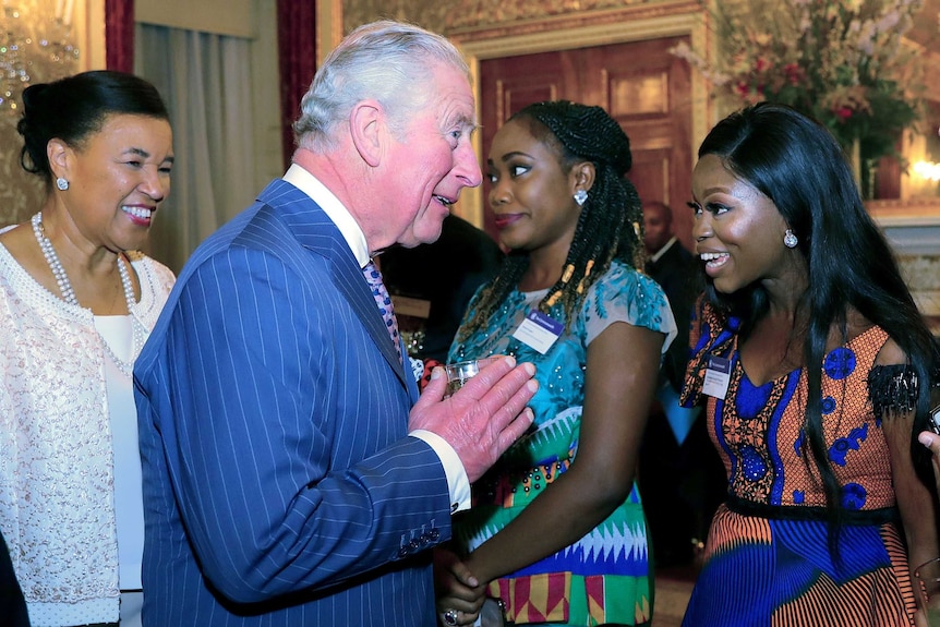 Prince Charles holding a drink while speaking to Oluwaseun Ayodeji Osowobi