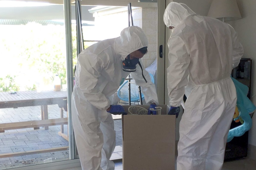 two men dressed in white suits pack boxes in house