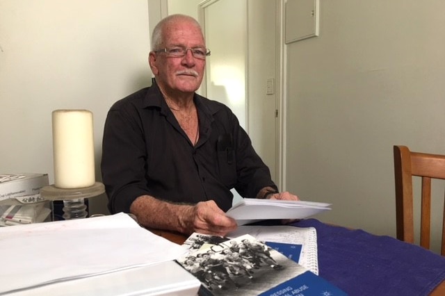 Allan Allaway sits a table with a number of books, folders, and documents.