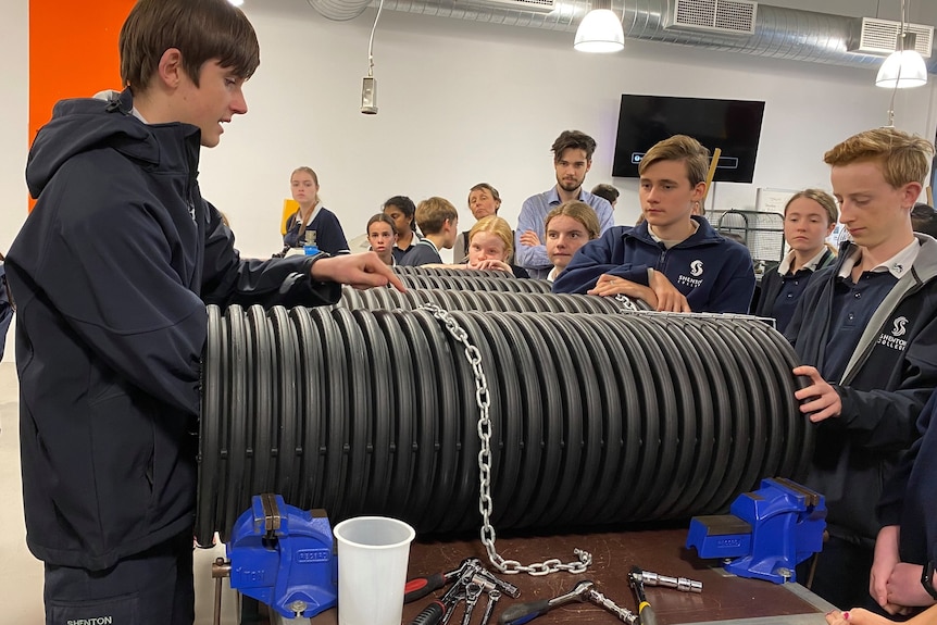 Students in a workshop gather around large plastic plastic tubes