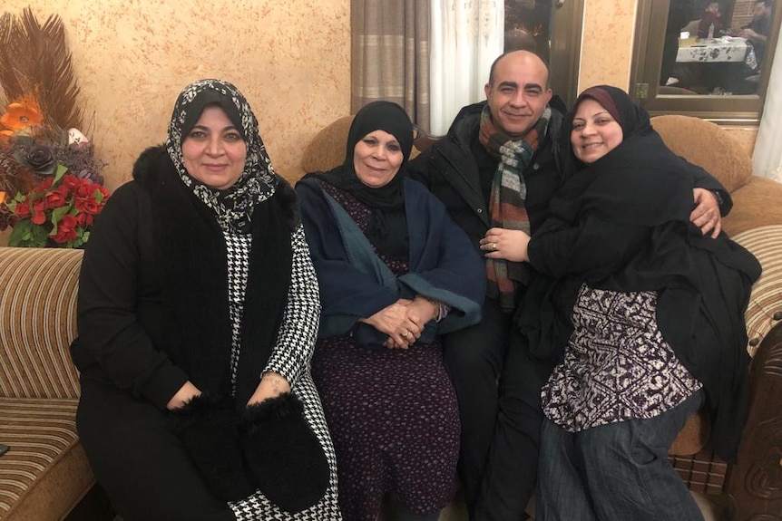 Three women in hijabs with one man smiling for a photo.
