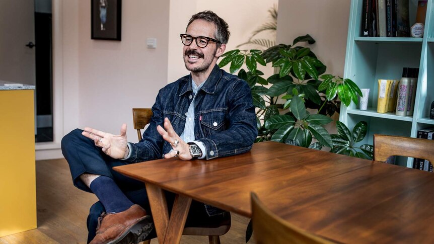 A man sitting at a table, laughing.