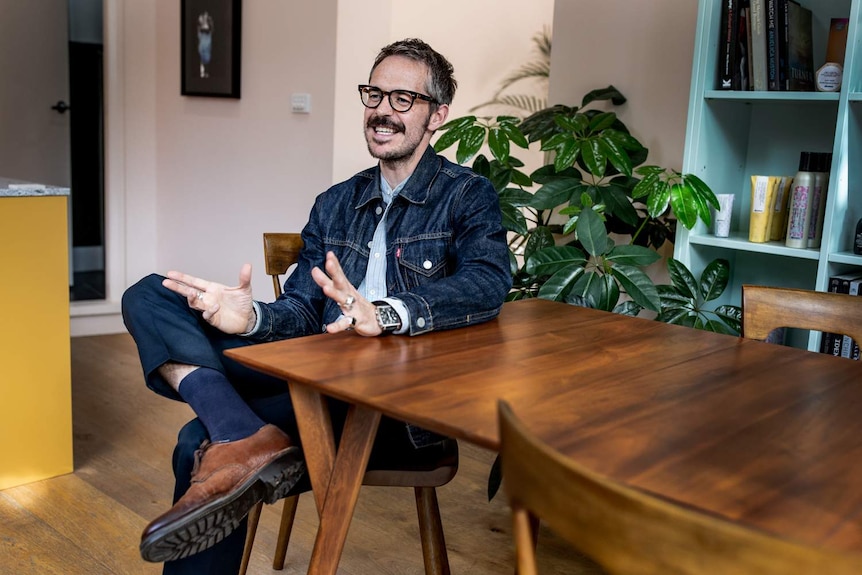 A man sitting at a table, laughing.