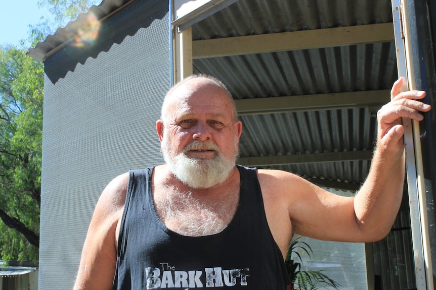 A man with a white beard standing outside.