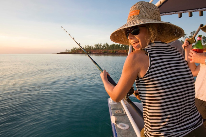 A woman sits in a boat with a fishing rod in the Top End.