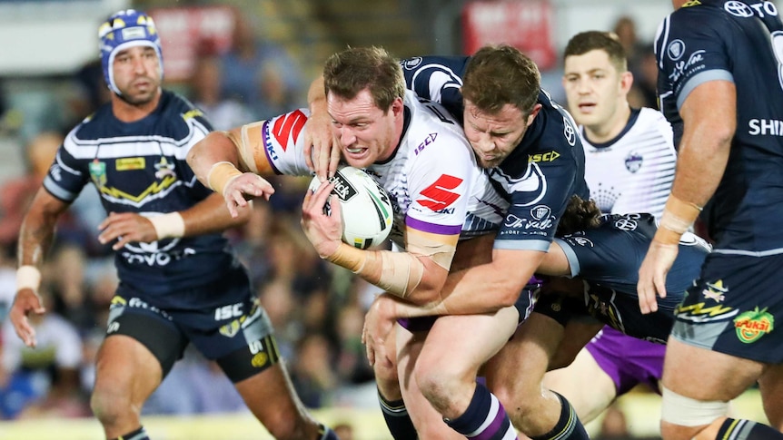 The Storm's Tim Glasby is tackled by the Cowboys in Townsville