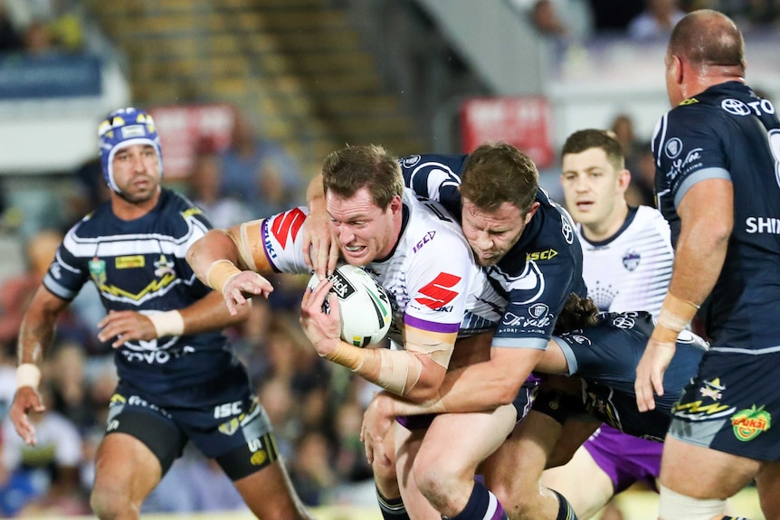 The Storm's Tim Glasby is tackled by the Cowboys in Townsville