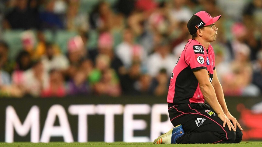 Steve O'Keefe of the Sydney Sixers pouts his lips while on his knees in the outfield during a Big Bash League game.