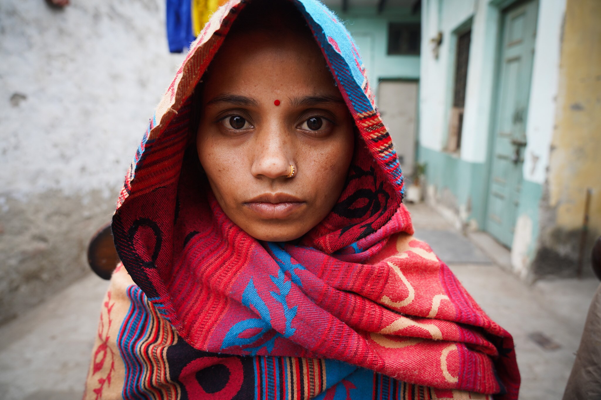 A close up of a woamn wearing a headscarf staring at the camera.