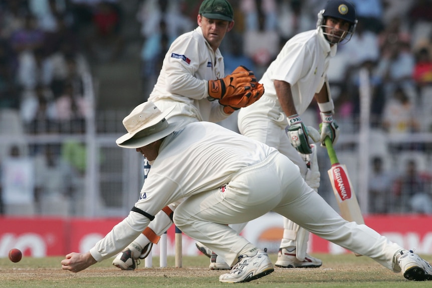 Matthew Hayden reaches down to try and catch a ball as Adam Gilchirst looks on