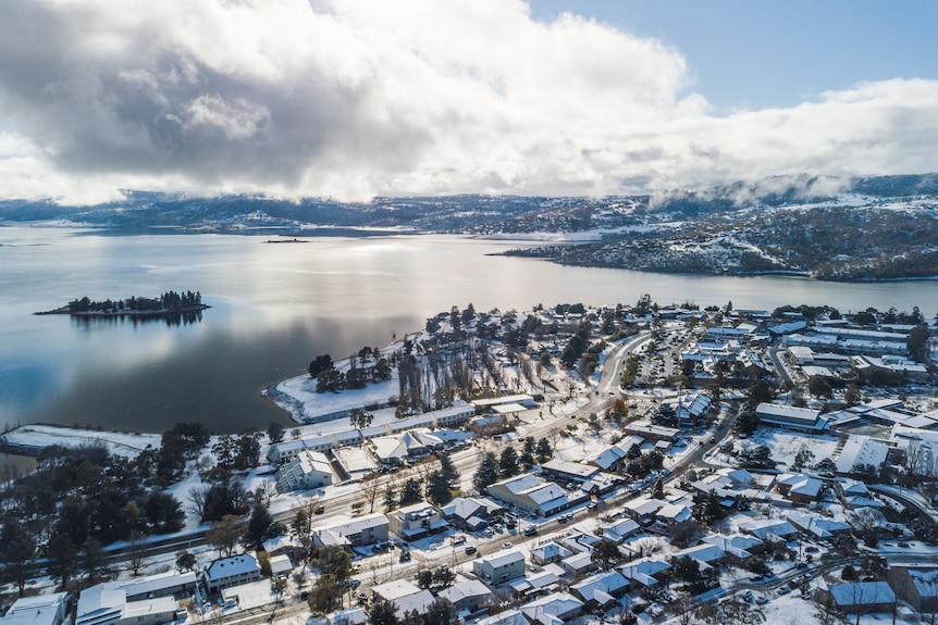 A drone shot of a town by a lake with snow.