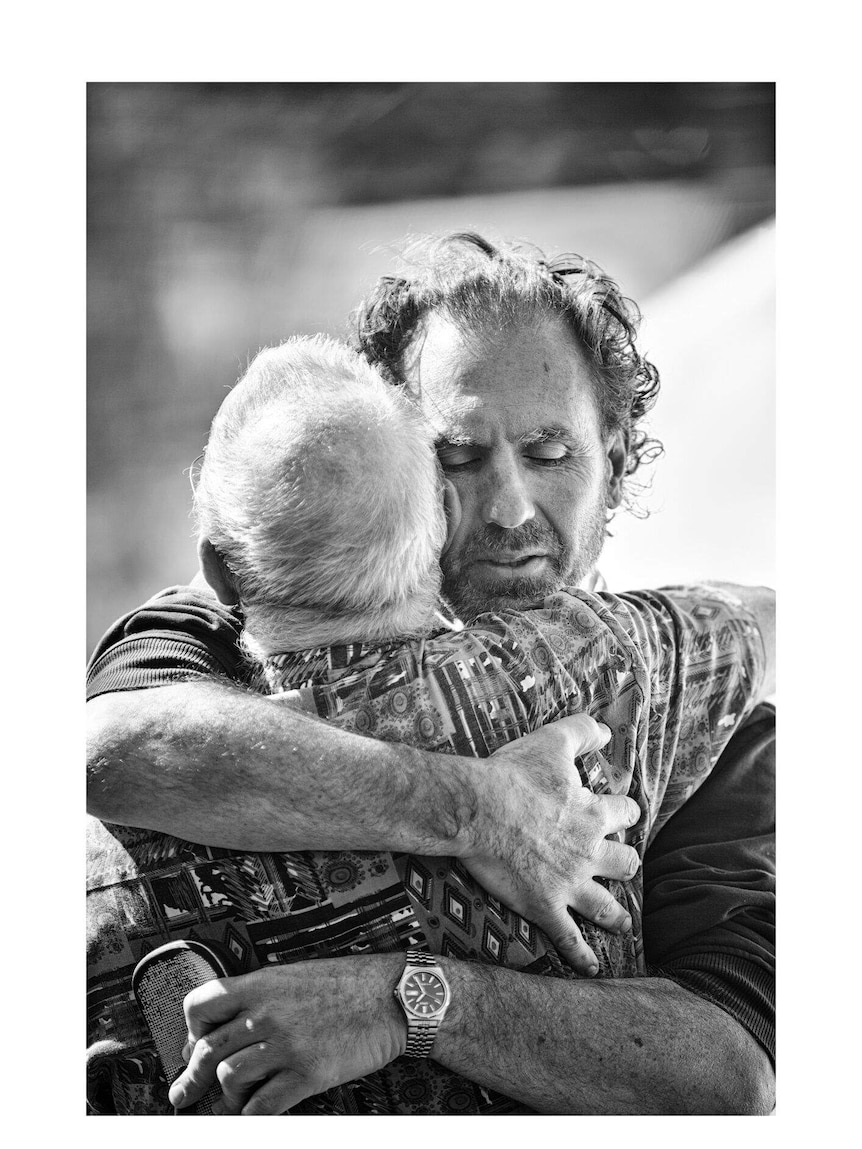 Black and White photo of two men hugging from Men With Heart exhibition.