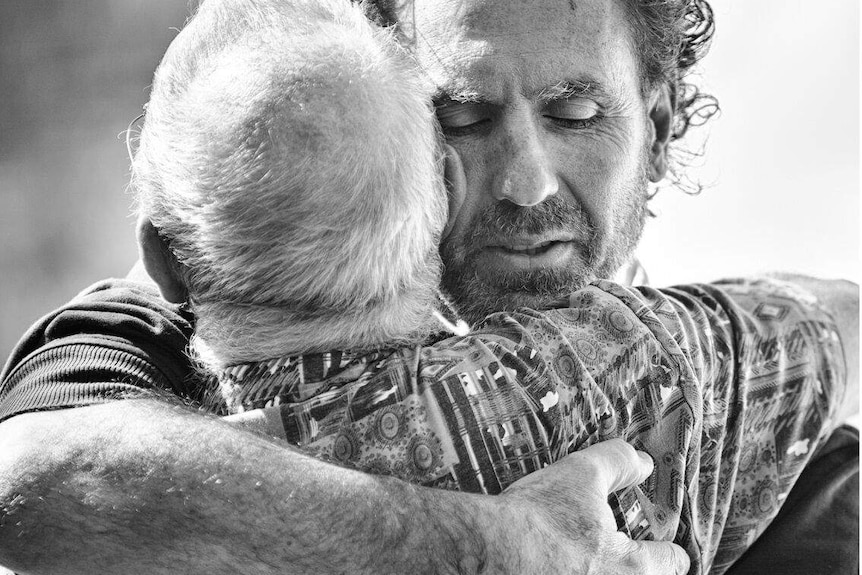 Black and White photo of two men hugging from Men With Heart exhibition.