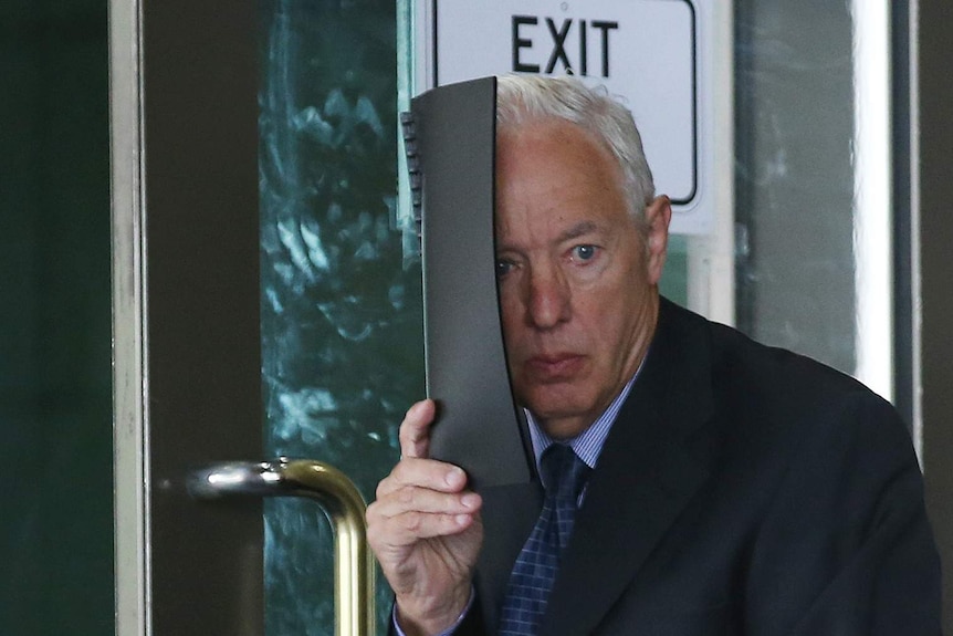 Former Christian Brother Stephen Farrell tries to cover his face as he leaves the Melbourne Magistrate Court in Melbourne.