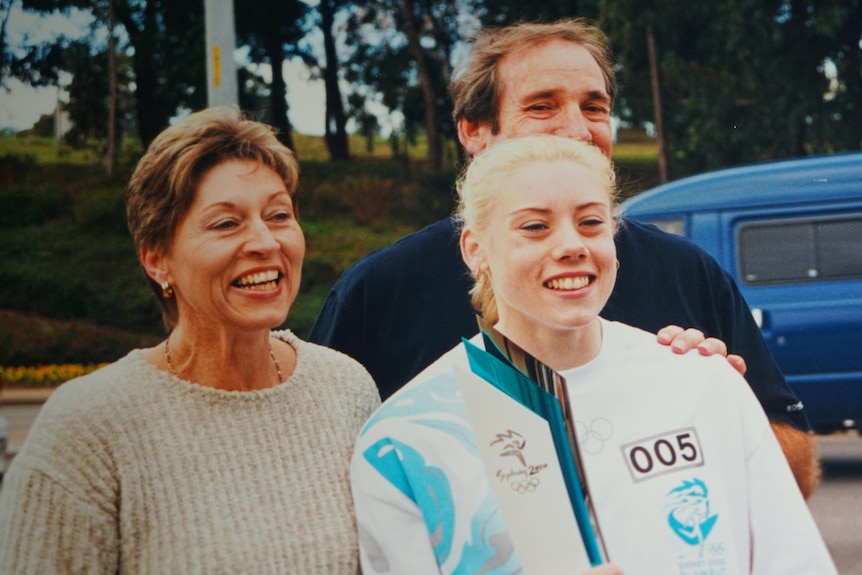 A young woman flanked by her parents.