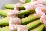 Slices of avocado topped with prawns and a mayonnaise sauce.