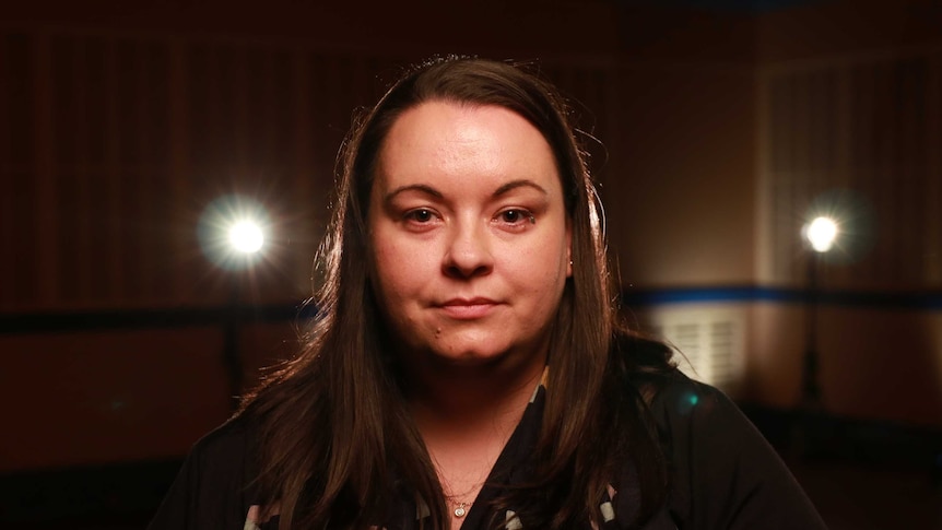 A woman poses for a photo in a studio