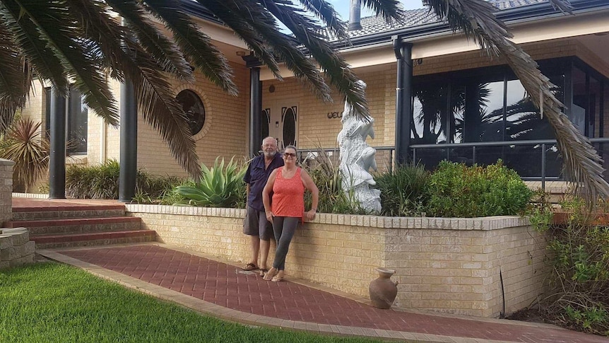 The pair stand out the front of their brick house.