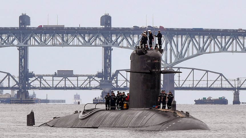 French submarine FNS Amethyste passes a bridge as officers stand onto of the vessel.