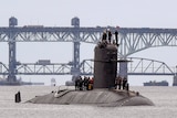 French submarine FNS Amethyste passes a bridge as officers stand onto of the vessel.