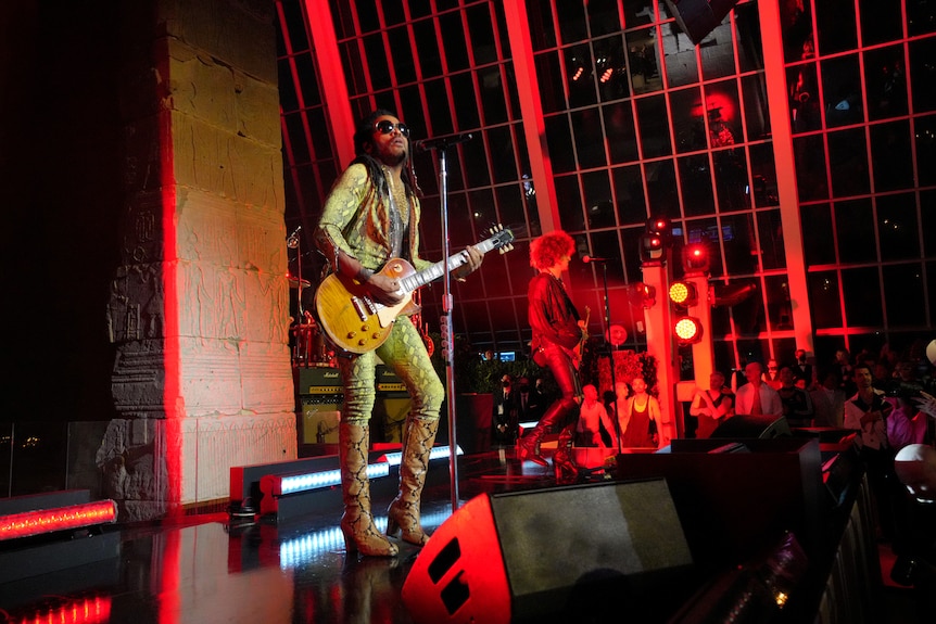 musician lenny kravitz plays guitar on stage at the met gala wearing a sparkly gold-coloured outfit