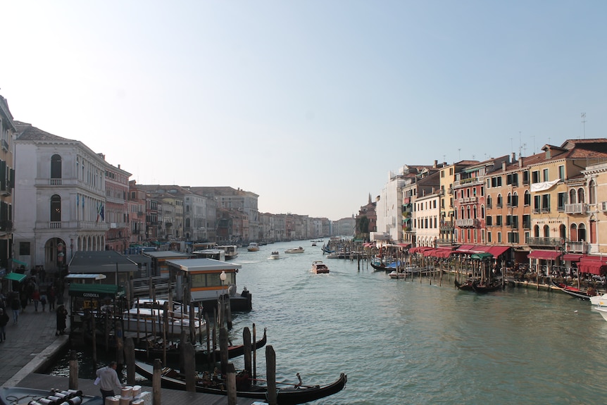 A large channel is Venice is pictured. On the left are gondolas.